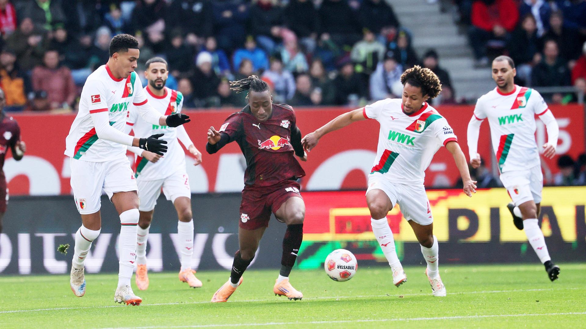 Leipzigs Yan Diomande wird von mehreren Augsburger Spielern verteidigt | IMAGO/Picture Point LE