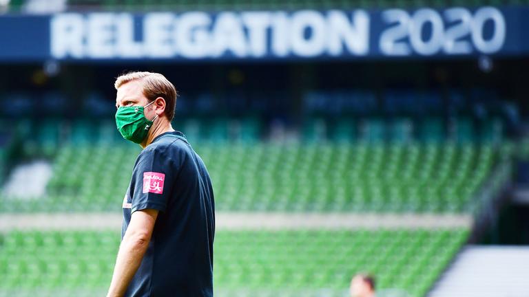 Werder Bremens Trainer Florian Kohfeldt vor einem großen Schild mit der Aufschrift "Relegation 2020". | Groothuis/Witters/Pool/Witters Werder Bremens Trainer Florian Kohfeldt vor einem großen Schild mit der Aufschrift "Relegation 2020".