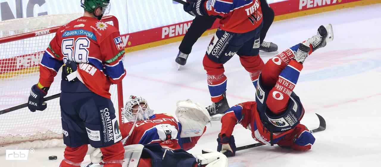 Kuriose Spielszene: Mehrere Eisbären-Spieler sind vor dem eigenen Tor, einer landet kopfüber auf dem Eis, der Torwart liegt auf dem Rücken, der Puk ist im Tor. Bild: IMAGO / Nordphoto