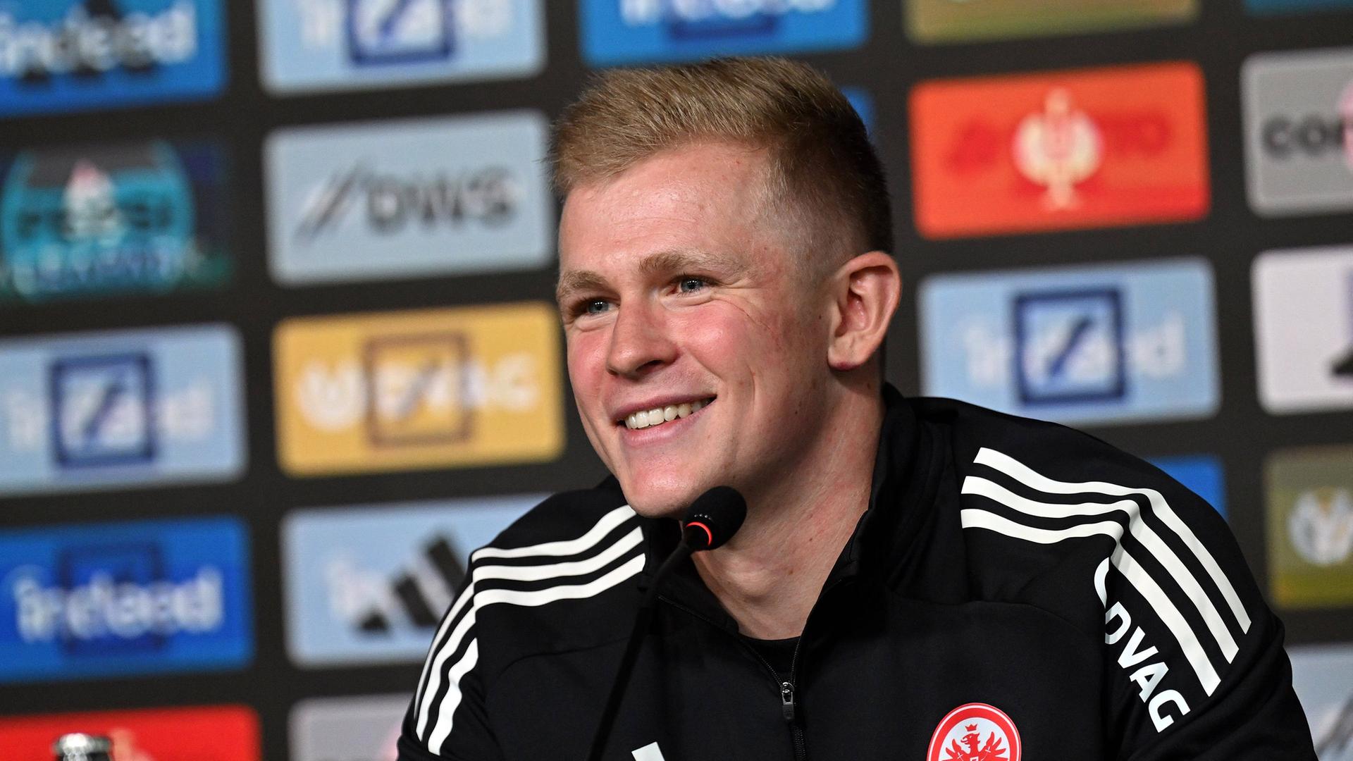 Eintracht-Neuzugang Jonathan Burkardt. Sitzt bei der PK und lacht. | Imago Images