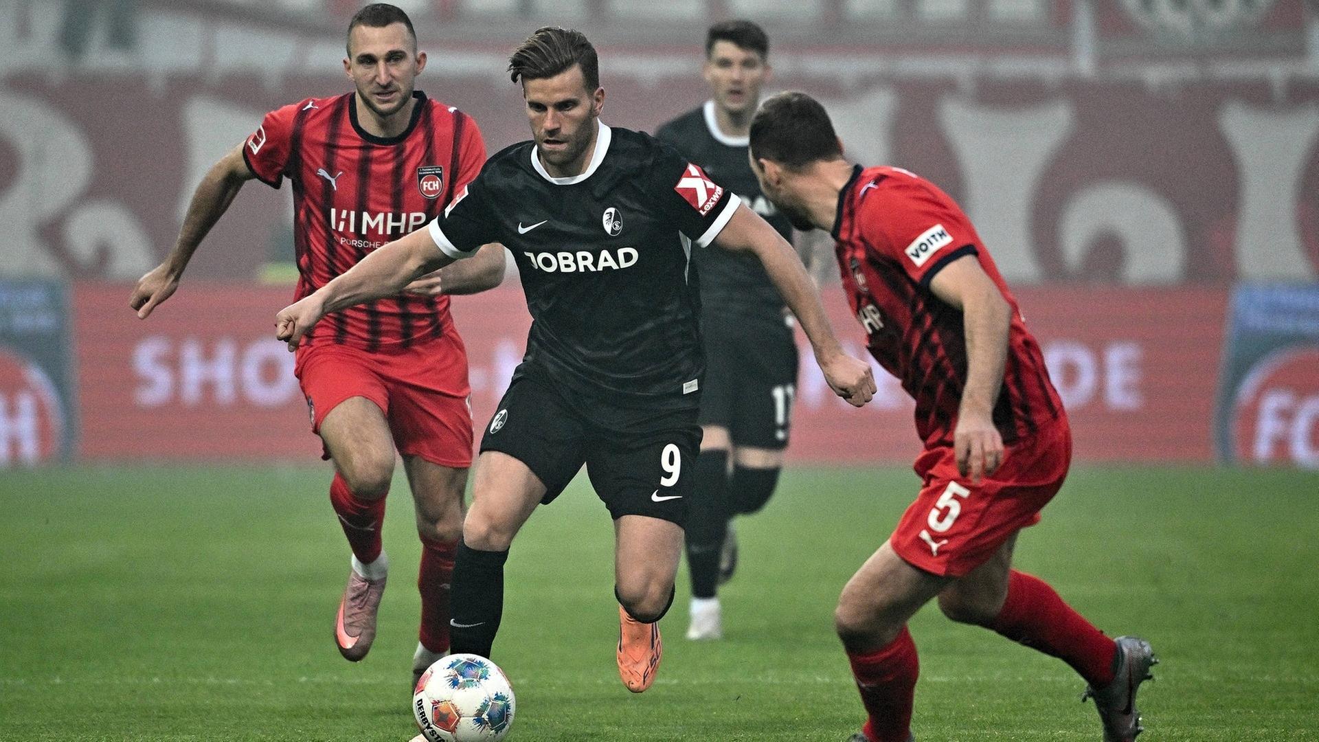 Freiburgs Lucas Höler (Mitte) kämpft mit Heidenheims Jonas Föhrenbach (li.) und Benedikt Gimber um den Ball | picture-alliance / Reportdienste, Picture Alliance