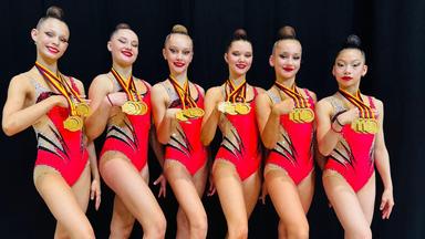 Sechs Mädchen posieren nebeneinander mit ihren Medaillen.