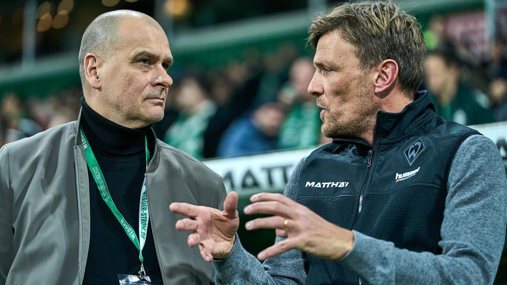 Werder-Chef Klaus Filbry steht mit dem Sportgeschäftsführer Clemens Fritz vor einem Spiel vor der Trainerbank und diskutiert. | Gumzmedia | Andreas Gumz