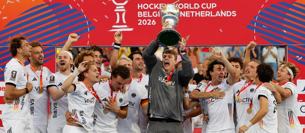 Die deutschen Hockey-Männer bei der WM-Siegerehrung 2026 mit WM-Pokal
