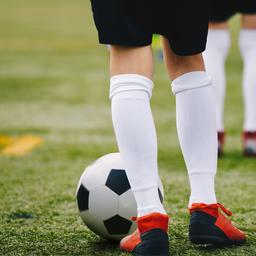 Kinderbeine in Fußballschuhen und Ball