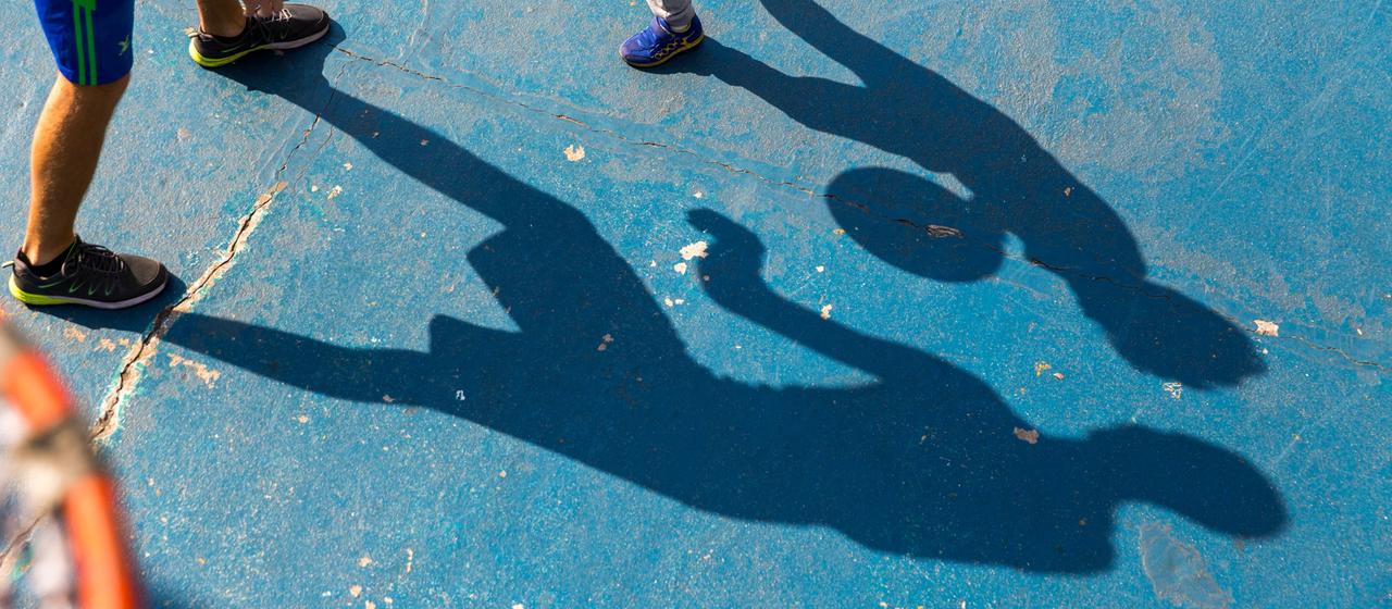 Ein Mann spielt mit einem Kind Basketball