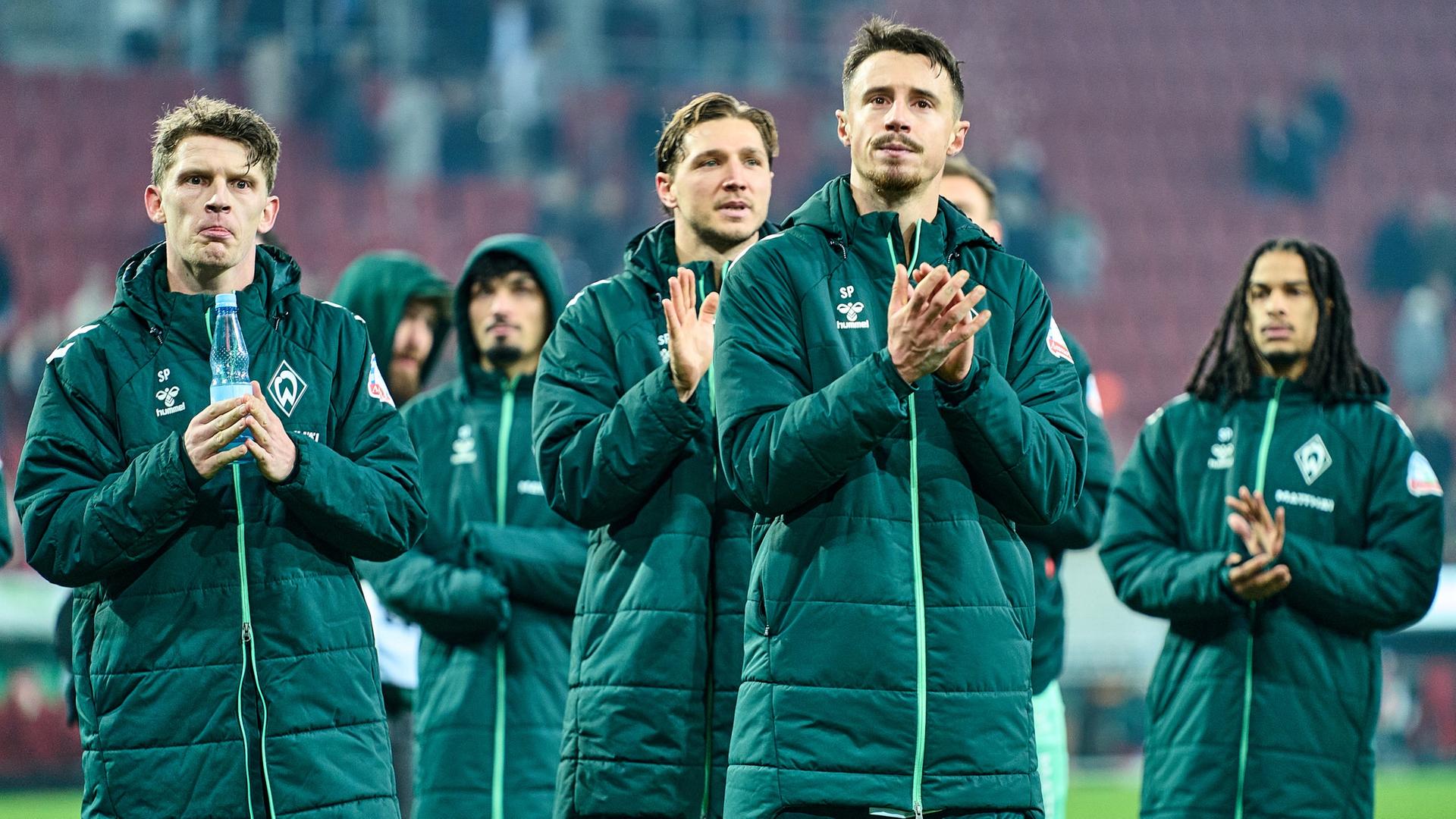 Mehrere Fußball-Profis von Werder Bremen um Kapitän Marco Friedl applaudieren nach dem Remis in Augsburg nachdenklich ihren Fans. | Gumzmedia | Andreas Gumz