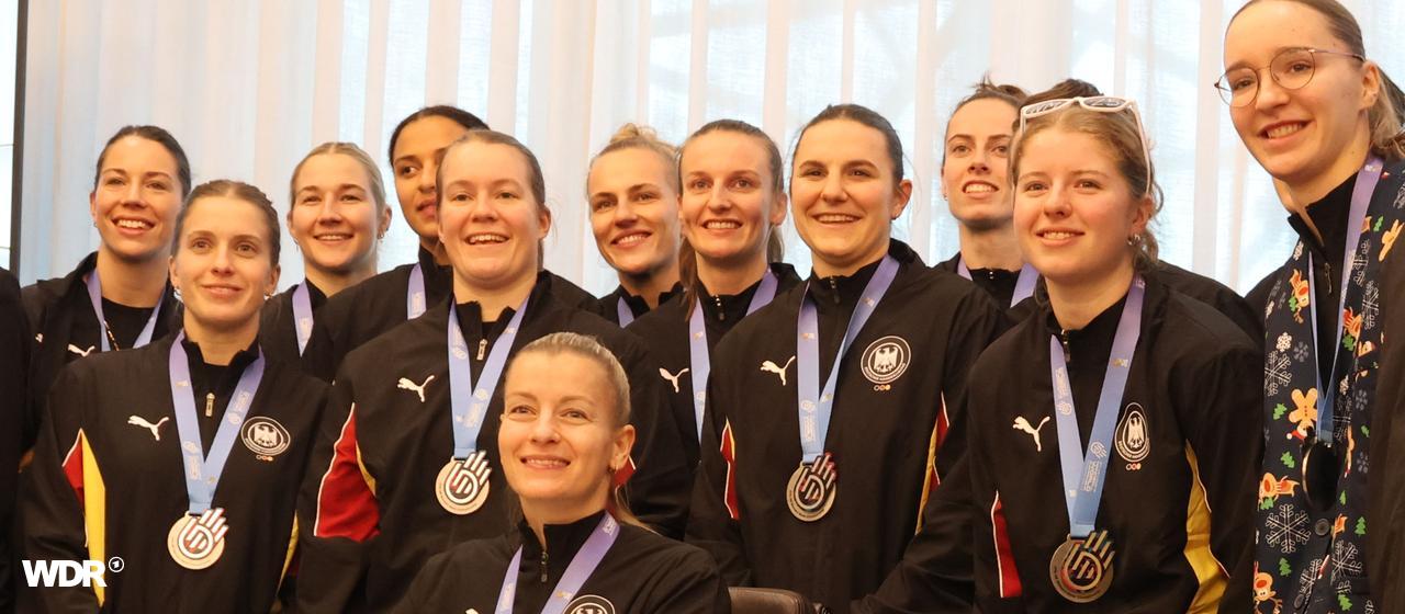 Die Handballnationalmannschaft der Frauen steht um einen Schreibtisch in Dortmund. Dort tragen sie sich ins Goldene Buch der Stadt ein.