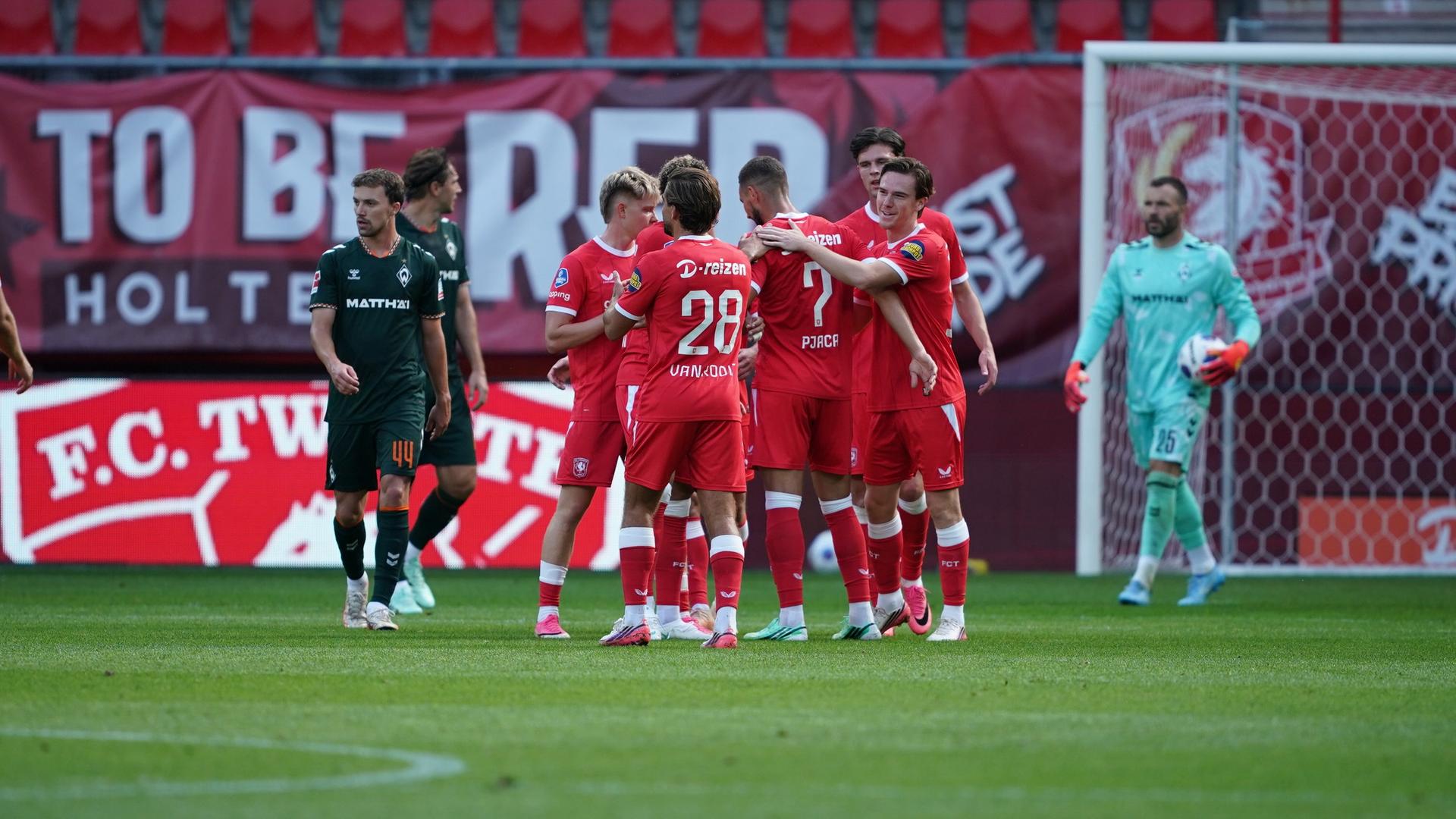 Einige Fußball-Profis von Werder Bremen stehen frustriert auf dem Spielfeld, während die Gegner von Twente Enschede gemeinsam ein Tor bejubeln. | Gumzmedia | Andreas Gumz