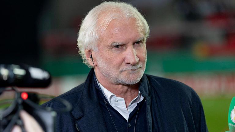 Rudi Völler mit Kopfhörern in einem Fußballstadion 