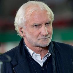 Rudi Völler mit Kopfhörern in einem Fußballstadion 