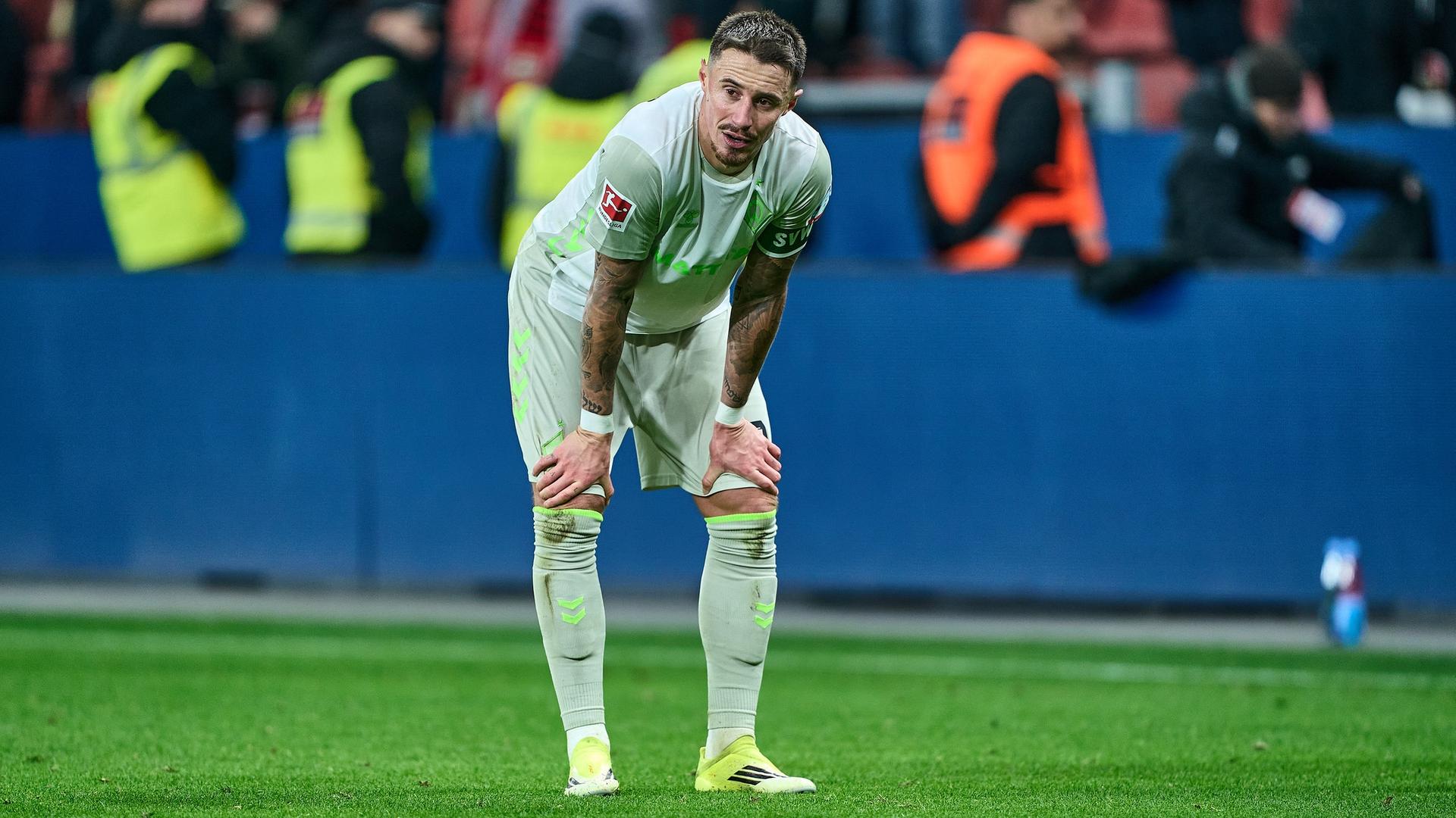 Werders Fußball-Kapitän Marco Friedl stützt nach der Niederlage gegen Leverkusen enttäuscht seine Hände auf die Knie. | Gumzmedia | Andreas Gumz
