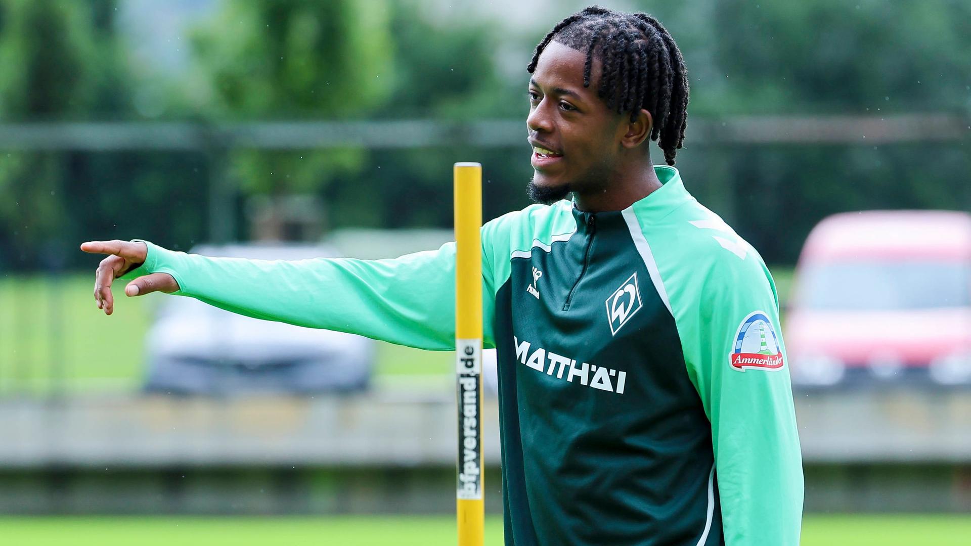 Werder-Neuzugang Samuel Mbangula steht im Zillertal auf dem Trainingsplatz und zeigt mit seinem rechten Arm etwas. | Imago | DeFodi Images