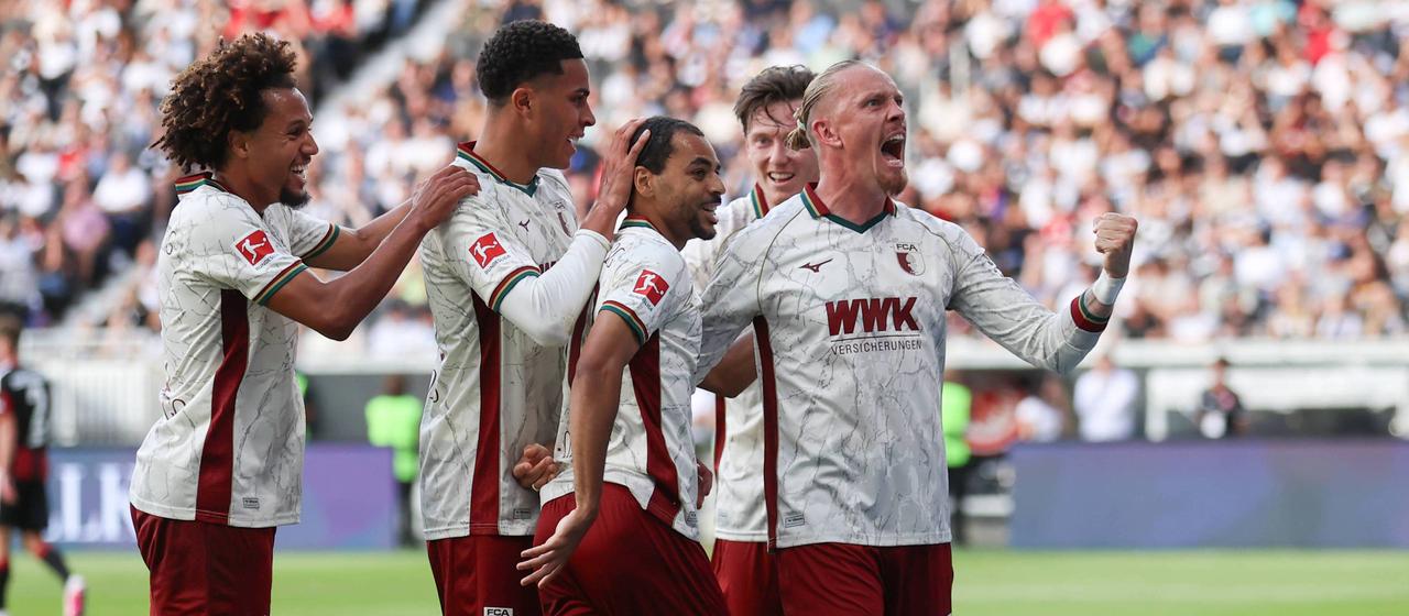 Fußballprofis des FC Augsburg bejubeln einen Treffer im Bundesligaspiel bei Eintracht Frankfurt