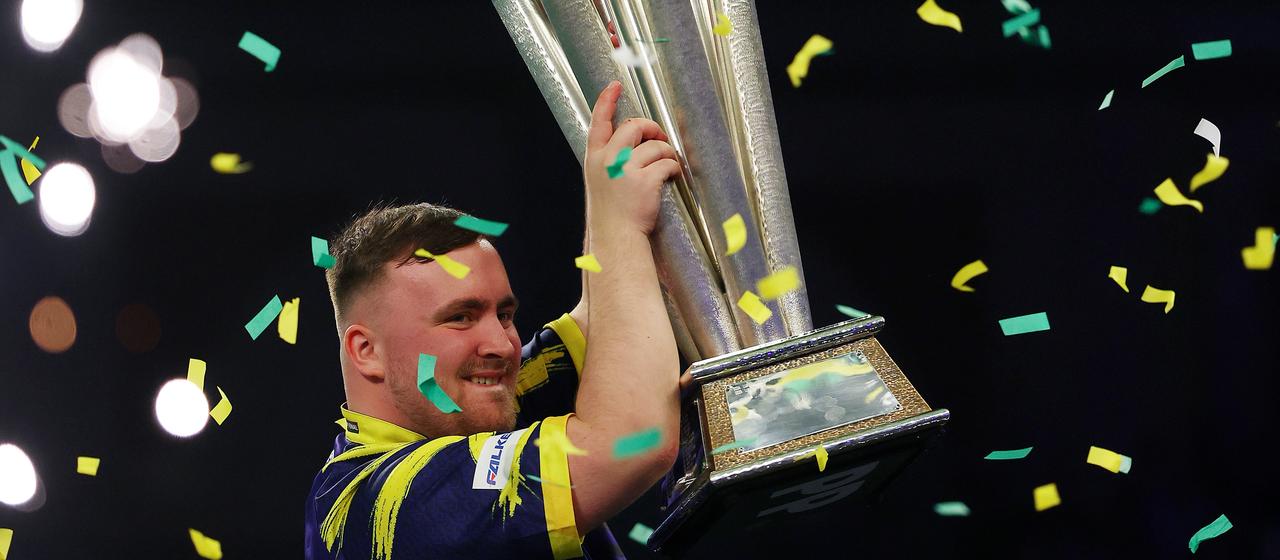 Luke Littler hält den WM-Pokal in die Höhe